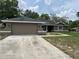 Tan single-story home featuring a two-car garage, green lawn, and a neutral color scheme at 12186 Lamont Dr, Spring Hill, FL 34608