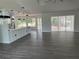Living room with gray vinyl flooring, kitchen, and sliding doors leading to the backyard at 12186 Lamont Dr, Spring Hill, FL 34608
