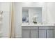 Modern bathroom featuring double vanity, gray cabinets, and large mirror at 17451 Whiskey Creek Trl, Parrish, FL 34219