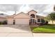 Peach-colored home with three-car garage, landscaped yard, and palm trees at 7612 Nottinghill Sky Dr, Apollo Beach, FL 33572