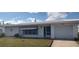 Charming single-story home featuring an attached garage, blue awning, and well-manicured lawn at 9350 Mainlands W Blvd, Pinellas Park, FL 33782