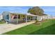 Single-wide yellow home with covered carport and green lawn at 233 Tarpon Ln, Oldsmar, FL 34677