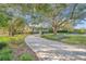 Two-story house with a brick driveway, surrounded by lush landscaping and large oak trees at 3010 82Nd N Way, St Petersburg, FL 33710