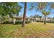 Landscaped backyard with a view of home's exterior and trees at 970 Rolling Hills Dr, Palm Harbor, FL 34683