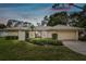 Tan one-story house with a two-car garage and manicured lawn at 970 Rolling Hills Dr, Palm Harbor, FL 34683
