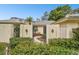Pathway to the front door of a tan house with lush landscaping at 970 Rolling Hills Dr, Palm Harbor, FL 34683