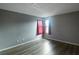 Bright bedroom with gray walls, wood-look floors, and a window with red curtains at 10212 Grant Creek Dr, Tampa, FL 33647