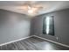 Bedroom with gray walls, wood-look floors, ceiling fan, and window with black curtains at 10212 Grant Creek Dr, Tampa, FL 33647