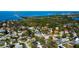 Aerial view of a coastal neighborhood featuring lush foliage and blue ocean water in the distance at 1612 Sunset Dr, Tarpon Springs, FL 34689