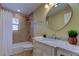 Bathroom features a shower, round mirror, and vanity with marble countertop at 1612 Sunset Dr, Tarpon Springs, FL 34689