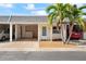 Front view of a condo with carport, landscaping, and palm trees at 224 Sky Loch E Dr, Dunedin, FL 34698