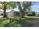 House exterior showcasing a manicured lawn, mature trees, and a two-car garage at 8134 Bayshore Dr, Seminole, FL 33776