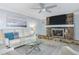 Open-concept living room with stone fireplace, plush sofa, and bright natural light at 8134 Bayshore Dr, Seminole, FL 33776