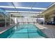 Enclosed pool area with clear water, tile deck, seating, and outdoor fan at 8134 Bayshore Dr, Seminole, FL 33776