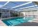 Sparkling enclosed pool with tile deck, surrounded by lush landscaping at 8134 Bayshore Dr, Seminole, FL 33776