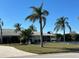Scenic view of a waterfront home featuring palm trees and lush landscaping at 10449 Larchmont N Pl, Pinellas Park, FL 33782