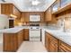Galley-style kitchen with wood cabinets and white appliances at 10449 Larchmont N Pl, Pinellas Park, FL 33782