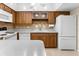 Kitchen with wood cabinets, white appliances, and tile countertops at 10449 Larchmont N Pl, Pinellas Park, FL 33782
