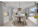 Bright dining area features a round wooden table set under a unique pendant light, with large windows providing natural light at 22847 Sonoma Ln, Lutz, FL 33549