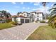 Stunning two-story home featuring a red-tiled roof, a paver driveway, and lush landscaping with palm trees at 22847 Sonoma Ln, Lutz, FL 33549