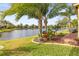 Landscaped backyard with lake view and lush tropical plants at 4817 Sandy Glen Way, Wimauma, FL 33598