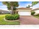 Inviting single-story home featuring a brick driveway, lush landscaping, and a two-car garage at 4817 Sandy Glen Way, Wimauma, FL 33598