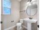 Well-lit half bathroom featuring pedestal sink, toilet, and round mirror at 4943 Grand Oak Cir, Madeira Beach, FL 33708