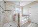 Bright bathroom featuring a glass-enclosed shower and separate soaking tub with elegant tile work and fixtures at 4943 Grand Oak Cir, Madeira Beach, FL 33708