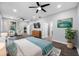 Bright main bedroom featuring hardwood floors, ceiling fan, a TV, and an adjacent sitting area at 11652 Palmetto Pine St, Riverview, FL 33569