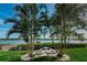 Landscaped backyard with palm trees, grill, and waterfront view at 19725 Gulf Blvd # 46, Indian Shores, FL 33785