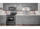 Modern kitchen with gray cabinets, quartz countertops, and stainless steel appliances at 200 Glennes Ln # 206, Dunedin, FL 34698