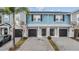 Three-unit townhome building with light blue siding, black garage doors, and a paved driveway at 2919 Grand Kemerton Pl, Tampa, FL 33618