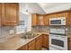 View of kitchen with wood cabinets, tile backsplash, and white appliances at 5430 Palm Crest N Ct, Pinellas Park, FL 33782