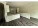 An open concept kitchen features white cabinetry, marble countertops, and new dark laminate flooring at 5725 Desert Rose Pl, Tampa, FL 33615