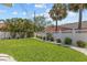 Manicured backyard featuring a lush lawn, white fence with floral accents, and tropical trees at 709 Mandalay Ave, Clearwater Beach, FL 33767