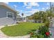 Spacious backyard with a green lawn, patio, white fence, and vibrant flower landscaping at 709 Mandalay Ave, Clearwater Beach, FL 33767