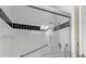 Updated shower with white tile, black accent, grab bars, and a glass door at 709 Mandalay Ave, Clearwater Beach, FL 33767
