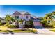 Two-story home with a pink exterior, gray metal roof, and palm trees at 620 Mirabay Blvd, Apollo Beach, FL 33572