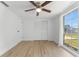 Bright bedroom with wood-look floors, large window and ceiling fan at 3438 Moog Rd, Holiday, FL 34691