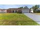 Brick ranch home with a two-car garage and grassy yard at 3438 Moog Rd, Holiday, FL 34691