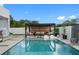 Modern pool featuring lounge seating with a pergola, and a patio area with tasteful landscaping in a backyard setting at 7602 Antilla St, Tampa, FL 33625