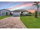 Single story home with a two-car garage and manicured lawn at sunset at 8705 Coastal Key Way, Parrish, FL 34219