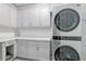 Modern laundry room with gray cabinetry, quartz countertops, and a stacked washer and dryer at 1009 Black Knight Dr, Valrico, FL 33594