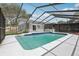 Full view of the in-ground pool with blue tile trim inside of the screened-in enclosure in a shady backyard at 1009 Black Knight Dr, Valrico, FL 33594