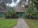 Green house exterior with brick walkway, palm trees, and a spacious yard at 17104 Rainbow Ter, Odessa, FL 33556