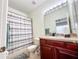 Clean bathroom with wood vanity, tub, and striped shower curtain at 30405 Elderwood Dr, Wesley Chapel, FL 33543