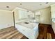 Open kitchen with white cabinets, a large kitchen island with quartz countertop, and hardwood floors throughout at 5727 Desert Rose Pl, Tampa, FL 33615
