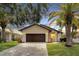 Charming single-story home with a brick-paved driveway and well-maintained landscaping, enhanced by the mature palm trees at 6208 Spoonbill Dr, New Port Richey, FL 34652