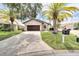 Inviting single-story home featuring a brick-paved driveway, lush lawn, and mature palm trees for a tropical curb appeal at 6208 Spoonbill Dr, New Port Richey, FL 34652