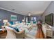 Virtually staged living room features a neutral color palette, hardwood floors, and comfortable wicker furniture at 703 Elkhorn Rd, Sun City Center, FL 33573
